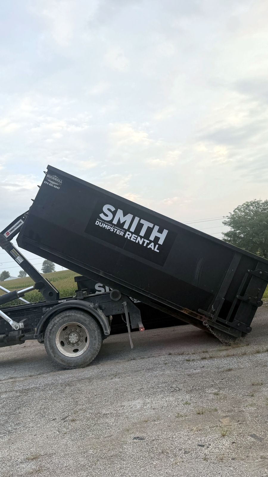 Smith Dumpster Rental truck loading a roll-off dumpster